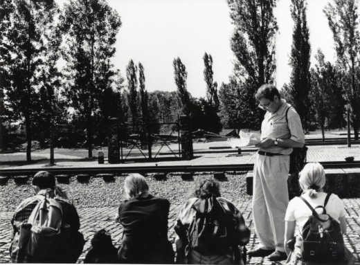 Sir Martin reading to his group of students at the railway line at Birkenau, just in front of the entrance gate and ruins of Crematorium III, June 1996